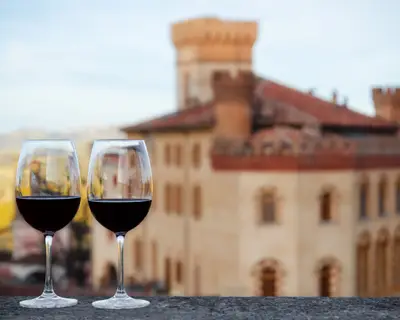 Two glasses of Barolo wine on a windowsill with the castle of Barolo (Piedmont, Italy) blurred on the background