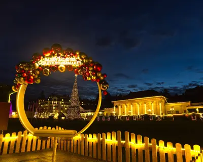 Festive Christmas Baden-Baden arch stand for touristic selfies with ornaments and lights overlooking illuminated casino and Christmas market at dusk
