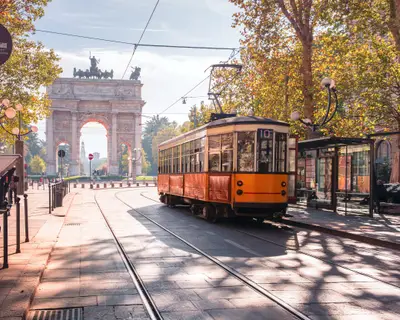 Famous vintage tram in the centre of the Old Town of Milan in the sunny day, Lombardia, Italy. Arch of Peace, or Arco della Pace on the background.