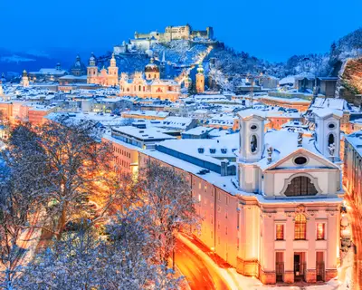 Salzburg, Austria: Winter view of the historic city of Salzburg with famous Festung Hohensalzburg and Salzach river illuminated in beautiful twilight during scenic Christmas time in winte
