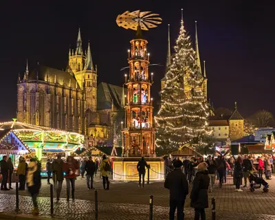 Erfurt, Germany. Christmas pyramid at Christmas market on Domplatz (Cathedral Square) in night. St Mary's Cathedral is visible in the background. Church of St Severus is hidden by the Christmas tree.