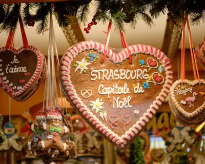 Gingerbread cookies in shape of hearts hanging from stall with messages of Christmas, Love and Strasbourg and a gingerbread man at the Strasbourg Christmas Market