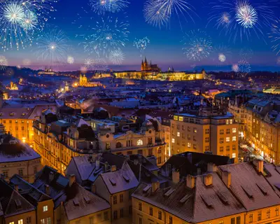 Prague Castle with snowy rooftops during late christmas sunset with blue sky and glowing street lights