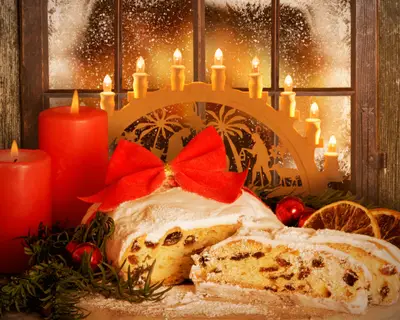 Weihnachtsstollen, Dresdner Stollen mit Schwibbogen vor winterlichem Fenster