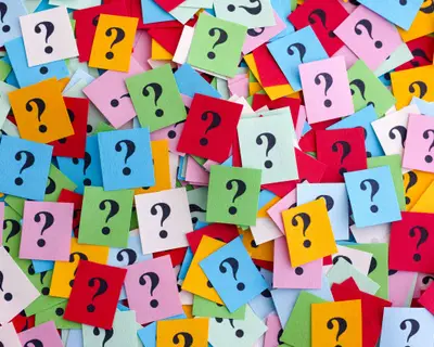Too Many Questions. Pile of colorful paper notes with question marks. Closeup.