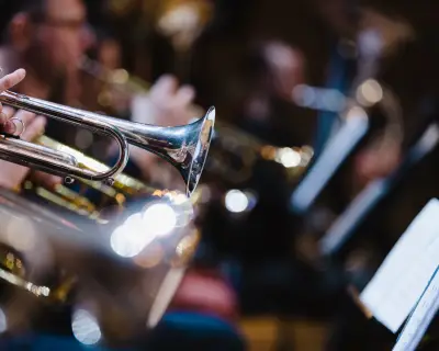 A musician playing a trumpet in a trumpet section of an orchestra during rehearsal